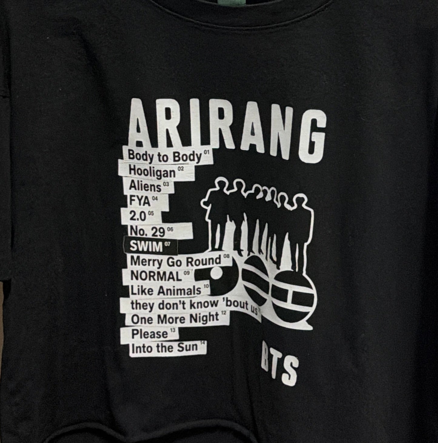 Black t-shirt with white text and graphics on a hanger against a white door background